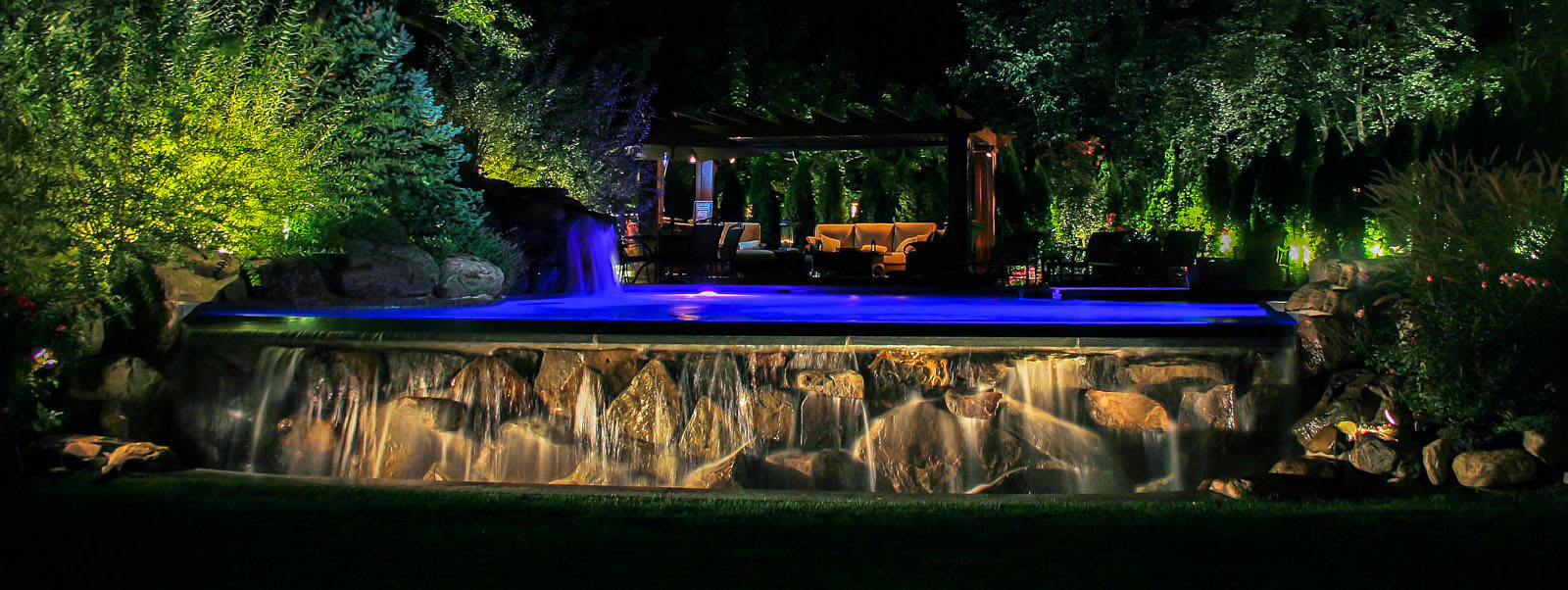 nj landscape lighting design illuminating pool, waterfall, pergola, and surrounding landscape