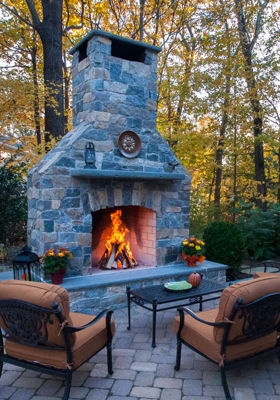 custom outdoor fireplace with fire burning inside