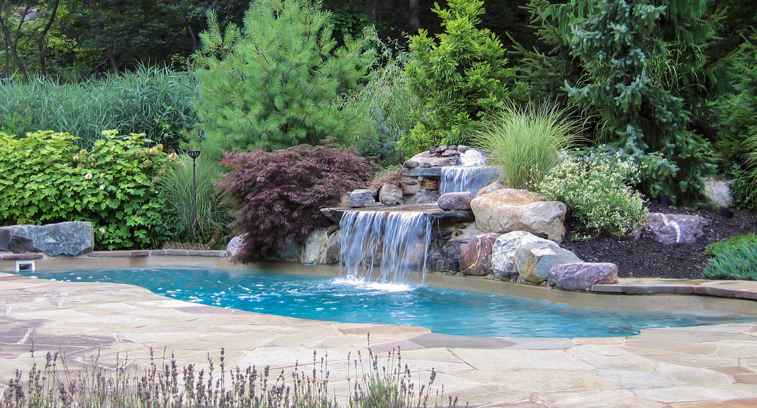custom nj pool with waterfall amongst pool landscaping