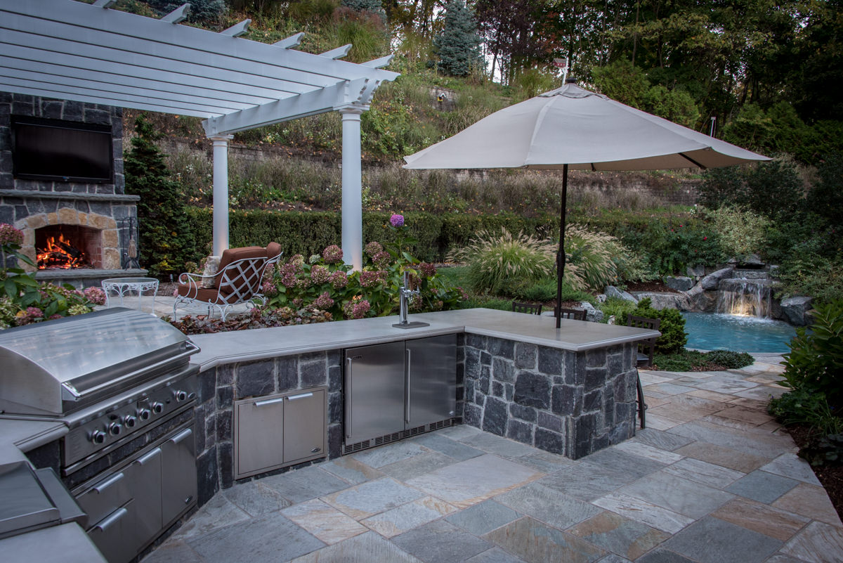 patio with outdoor kitchen, small pool in background