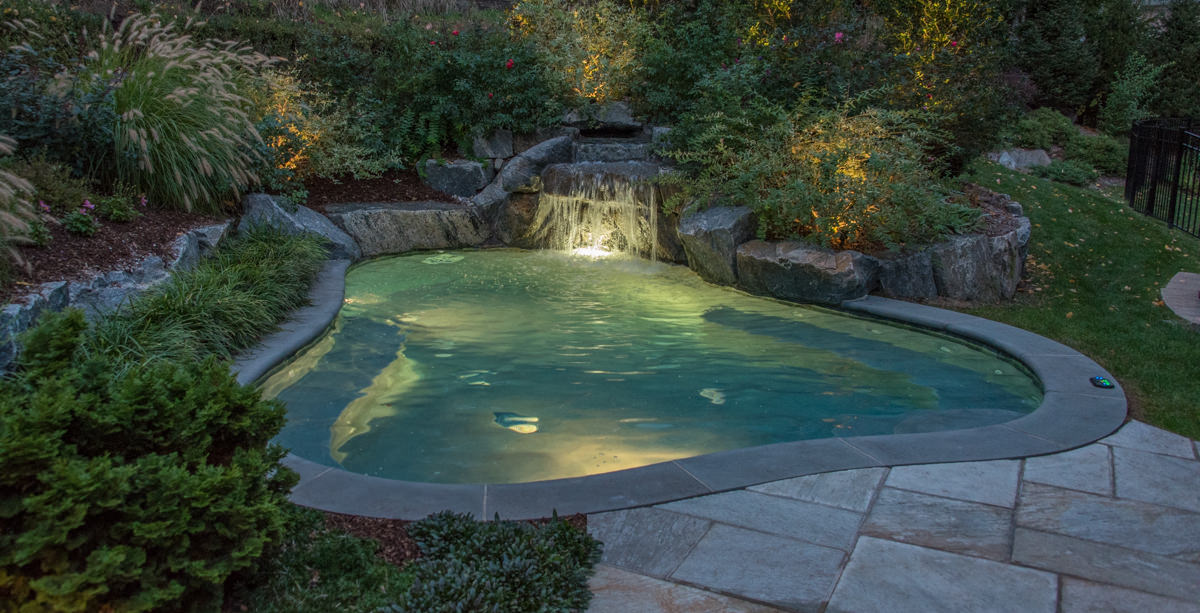 small pool in franklin lakes backyard with lighting and waterfall