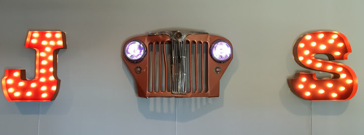 restored jeep willys grill with lights hanging on wall