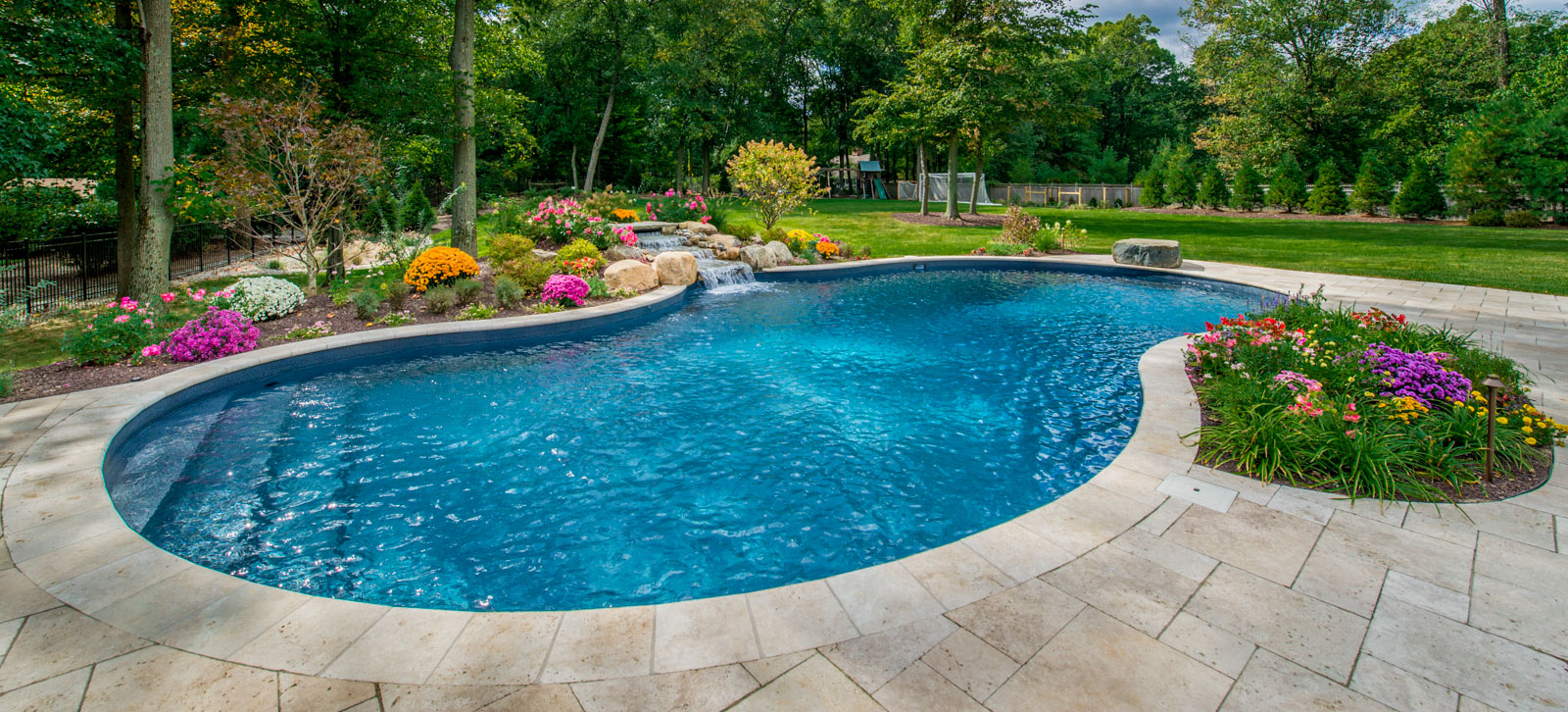 vinyl swimming pool with pool waterfall and flowers in pool landscape