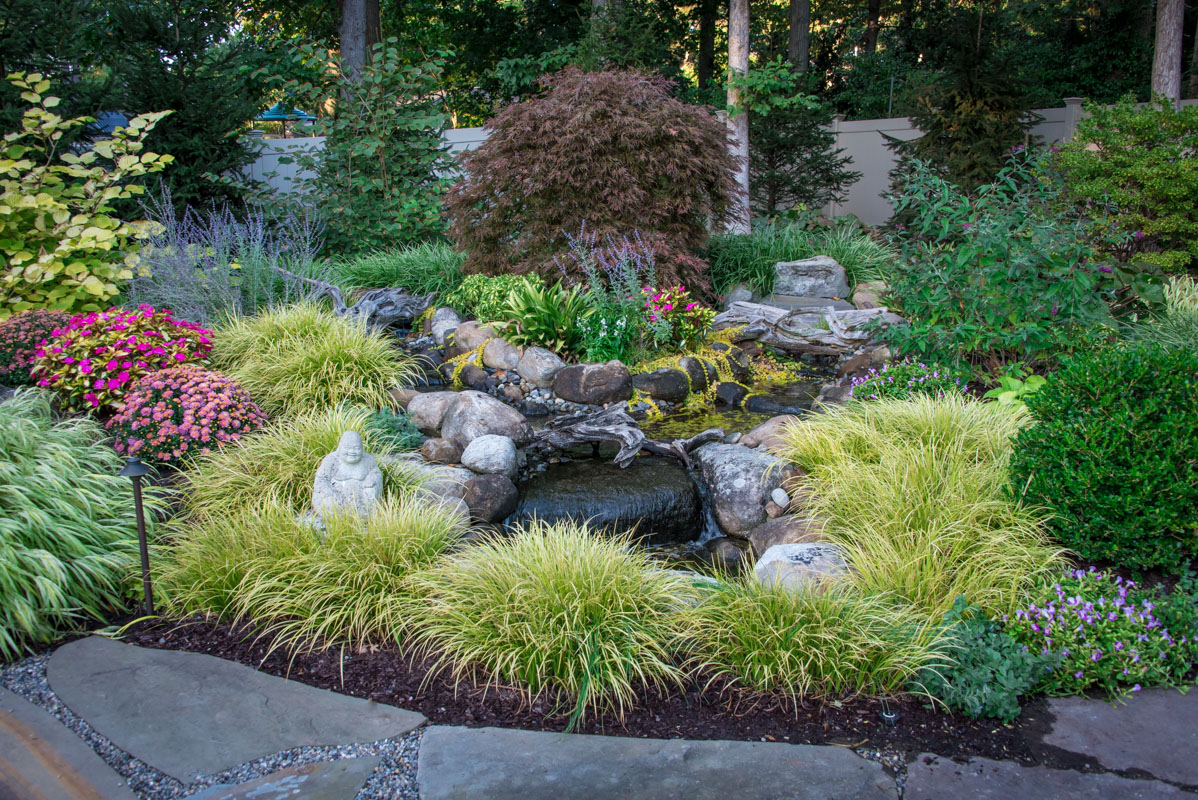 lush plantings surround water feature in northern nj landscape