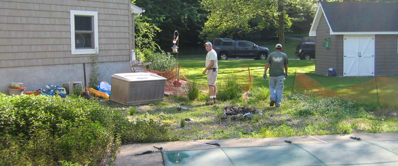 Before and after of a nighttime backyard renovation featuring a transformation from an empty yard into a glowing poolscape with spa, slide, waterfall, fireplace, and ambient lighting.