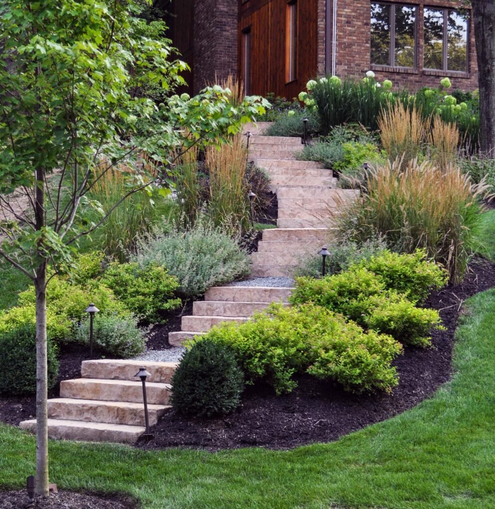 Before and after of a backyard renovation showing transformation from a patchy lawn to a luxurious poolscape with waterfall, raised spa, and natural stone patio.