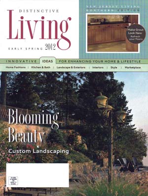 Cover of Distinctive Living magazine, Early Spring 2012 issue, featuring a landscaped hillside with terraced stone steps, custom lighting, and blooming trees, promoting custom landscaping services.