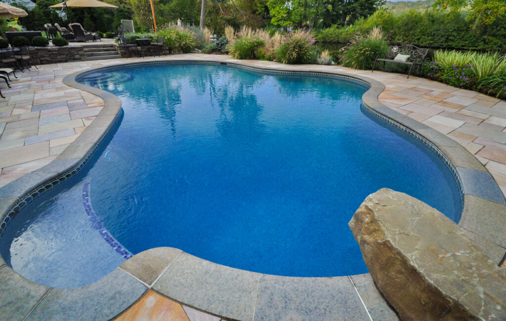 Natural woodland buffer with flowering shrubs and pond edge in Wayne landscape.