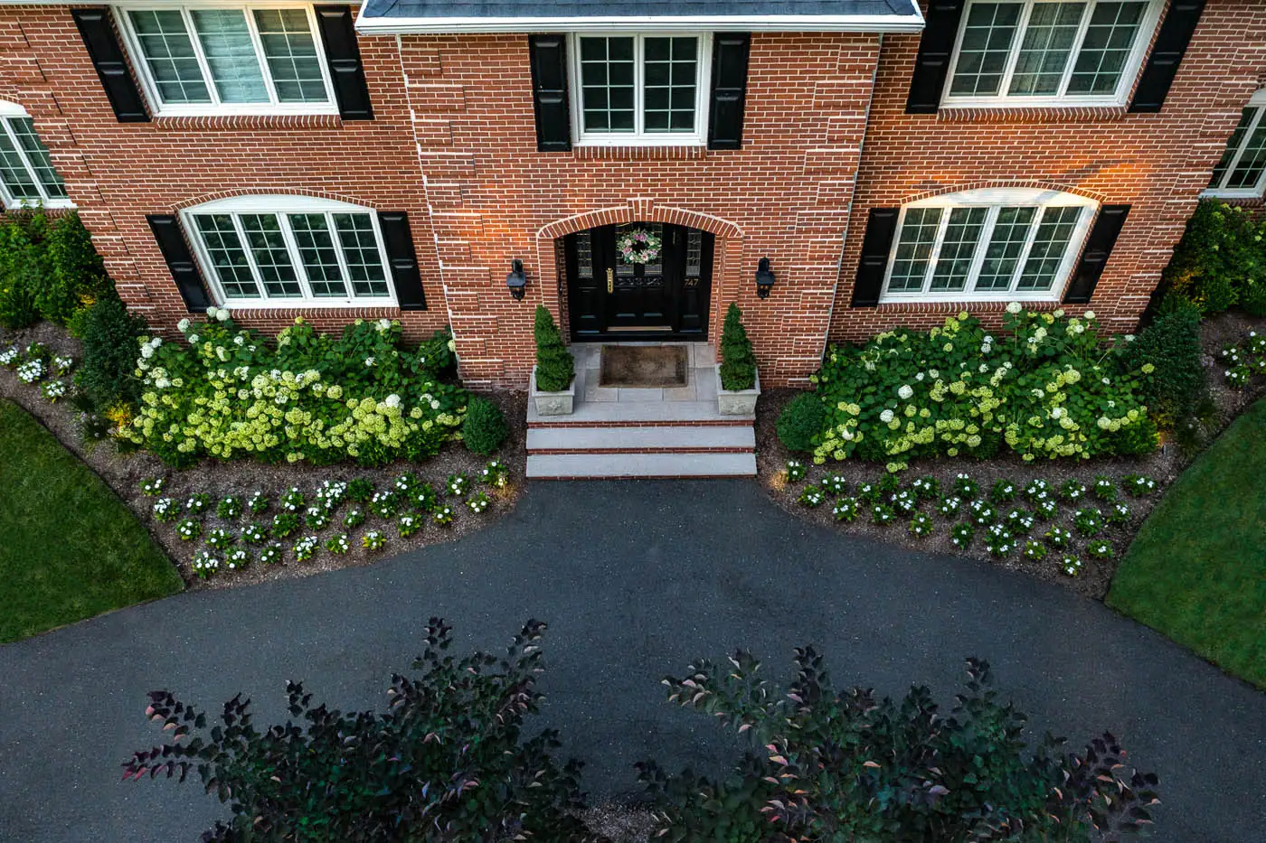 CLC Landscape Design front yard in Franklin Lakes, NJ—foundation planting featuring boxwoods, alliums, and layered perennials along the home and driveway