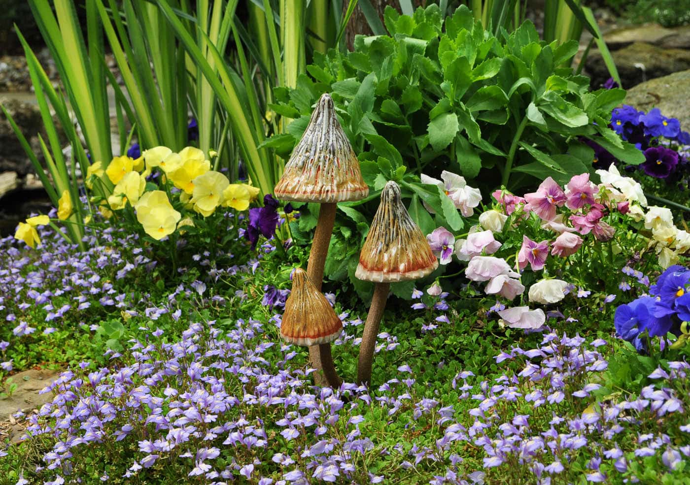 Magic‑infused spring garden sanctuary—vibrant blossoms, fresh green foliage, and playful ceramic mushrooms rising from a soft purple floral carpet.