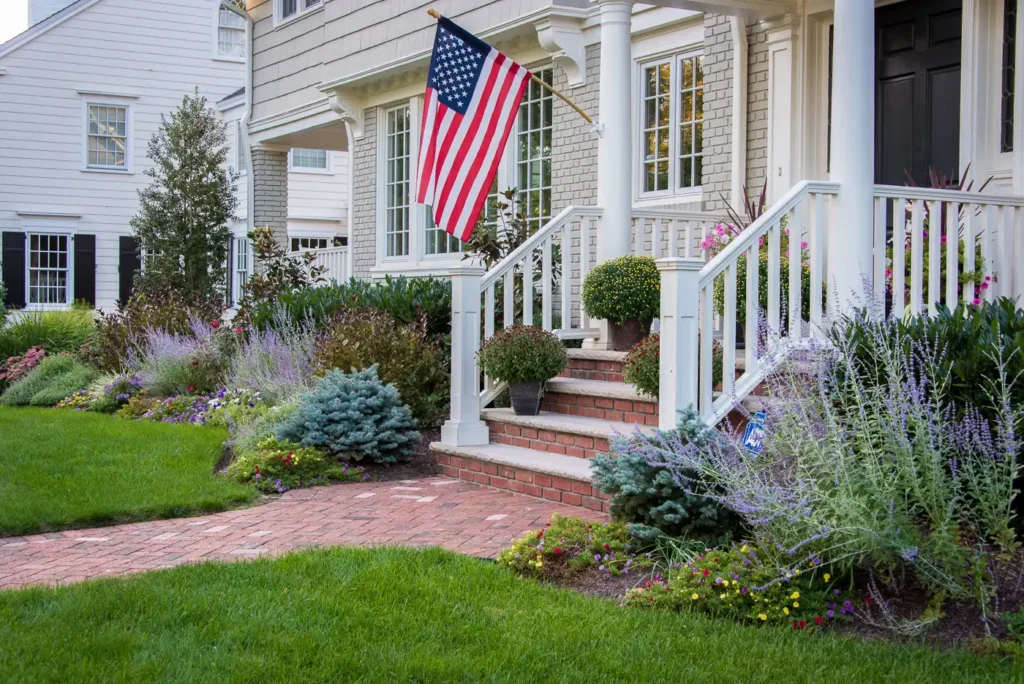 Front entry steps in Montclair, New Jersey by CLC Landscape Design featuring custom stonework, clean hardscape lines, and an American flag accent