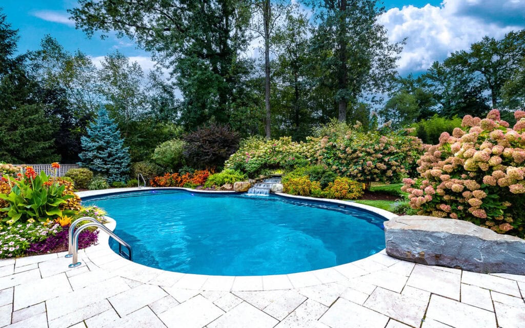 In-ground swimming pool with rock waterfall feature and landscaped patio by CLC Landscape Design & Pool Contractor serving Scotch Plains, New Jersey.