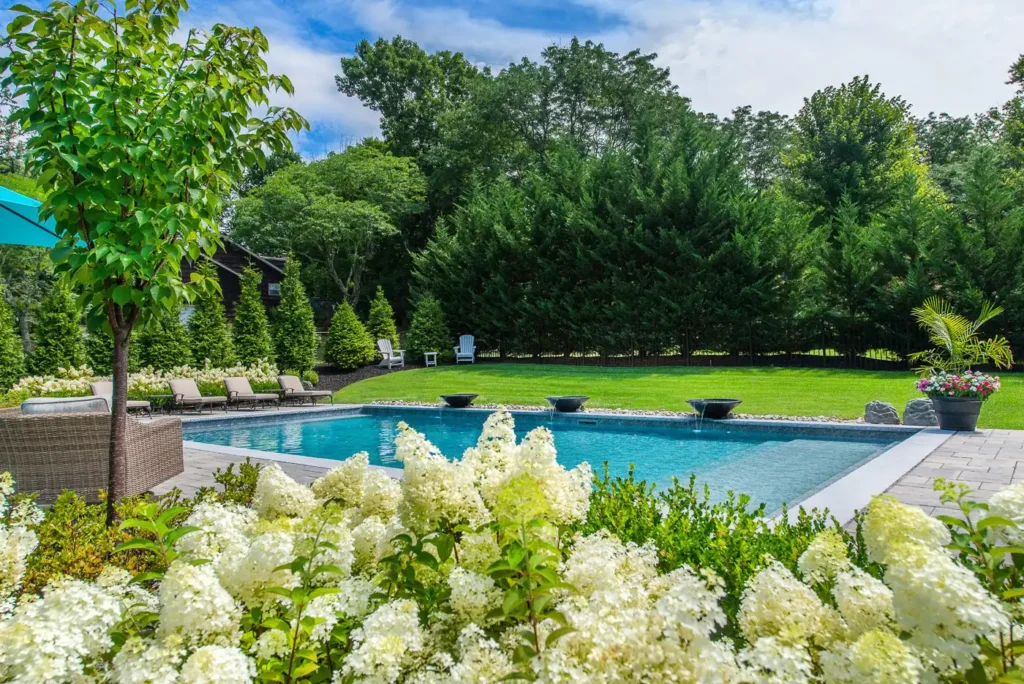 Backyard pool and hydrangea garden in Pine Brook, New Jersey by CLC Landscape Design featuring lush blooming hydrangeas, a custom swimming pool, and elegant outdoor landscaping