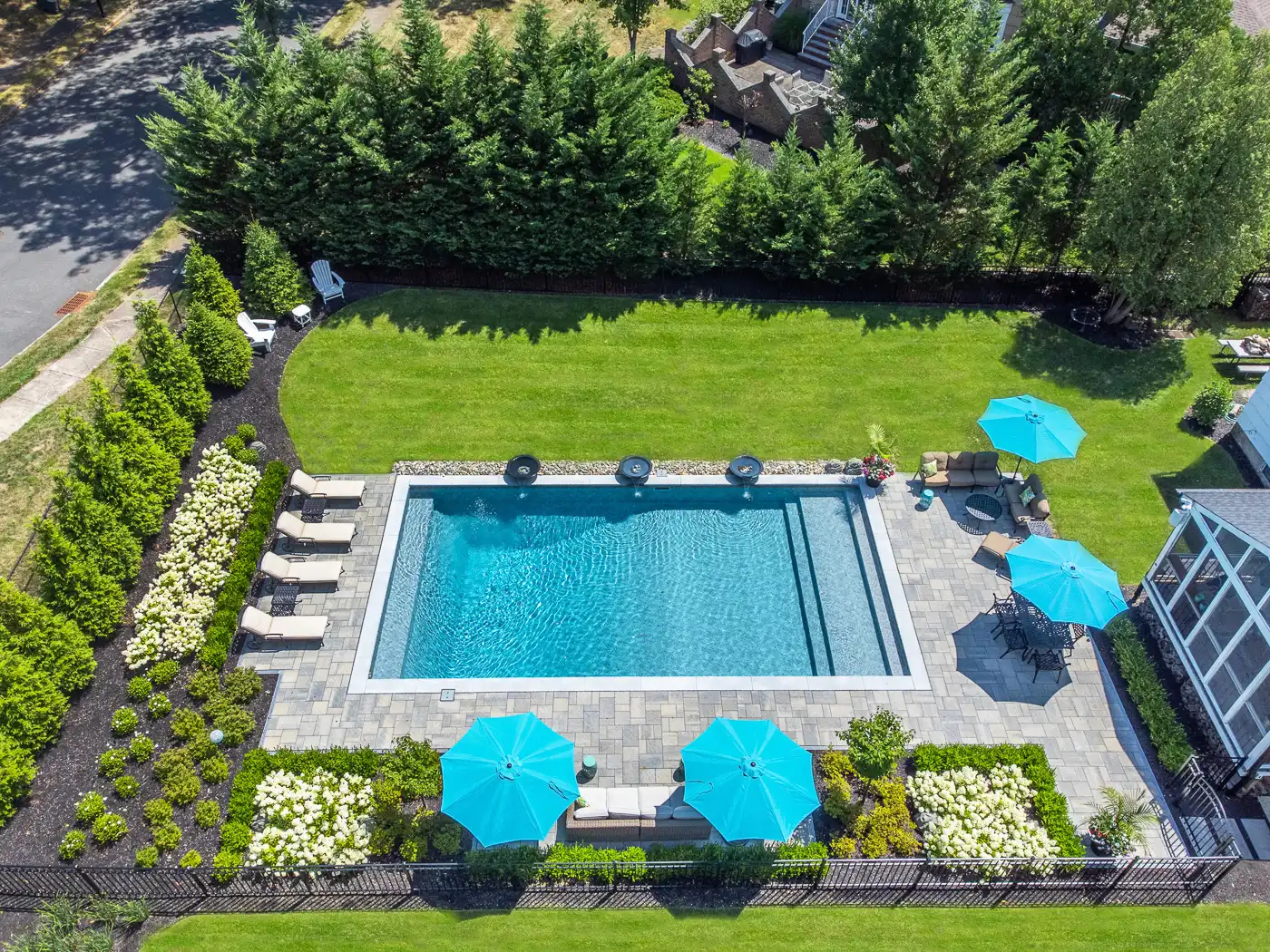 Backyard swimming pool in Pine Brook, New Jersey by CLC Landscape Design surrounded by full hydrangea blooms, layered landscaping, and a clean paver patio