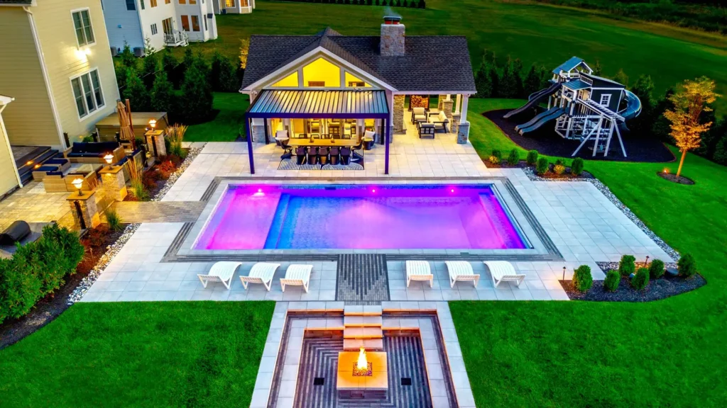 Custom swimming pool with surrounding landscape lighting and plantings in Upper Saddle River NJ by CLC Landscape Design